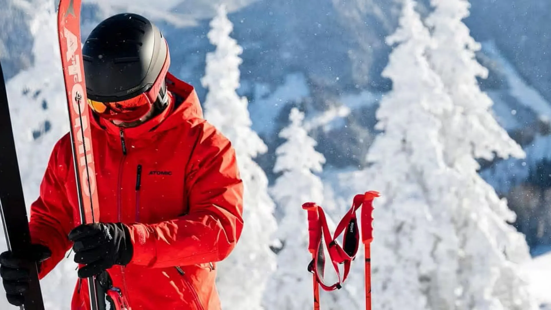 Skifahrer in roter Jacke auf schneebedecktem Berg